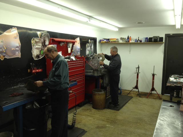 Hydra-Tech Transmissions - two mechanics looking at engine parts for vehicles in an engine shop