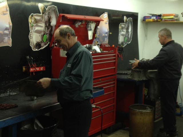 Hydra-Tech Transmissions - two mechanics looking at engine parts for vehicles in an engine shop